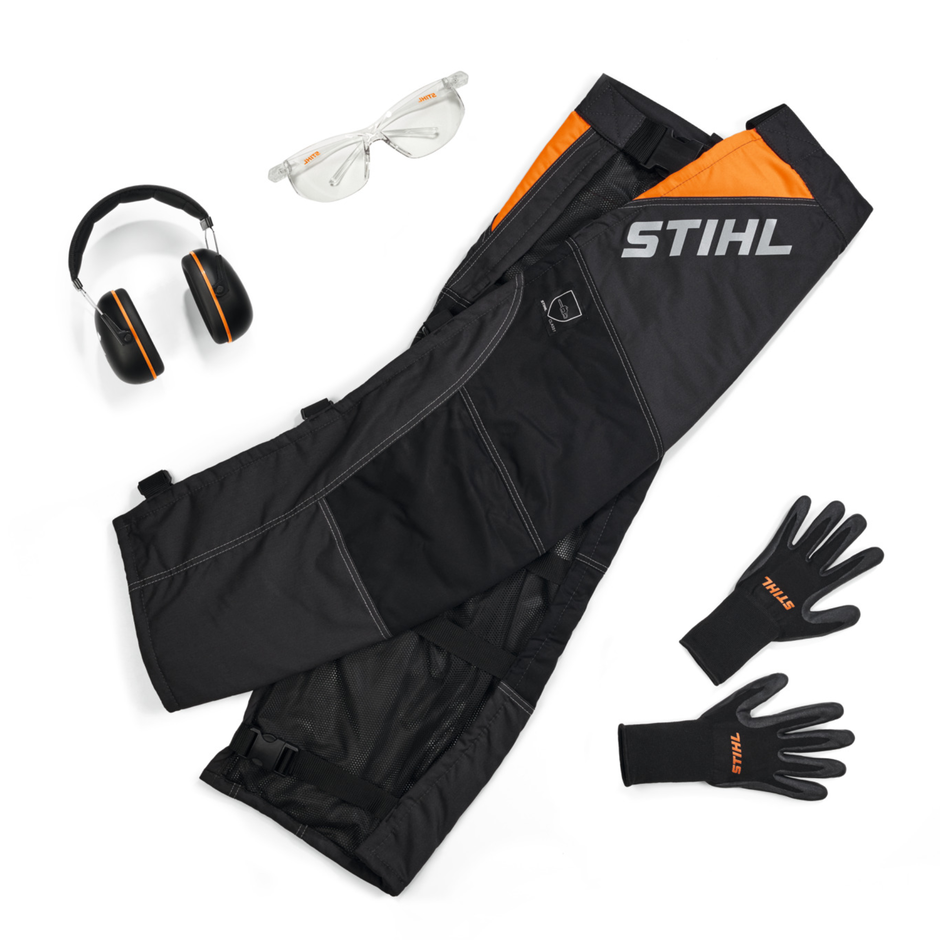 Accessorio di sicurezza STIHL: pantaloni protettivi, occhiali, cuffie antirumore e guanti per il lavoro all'aperto.